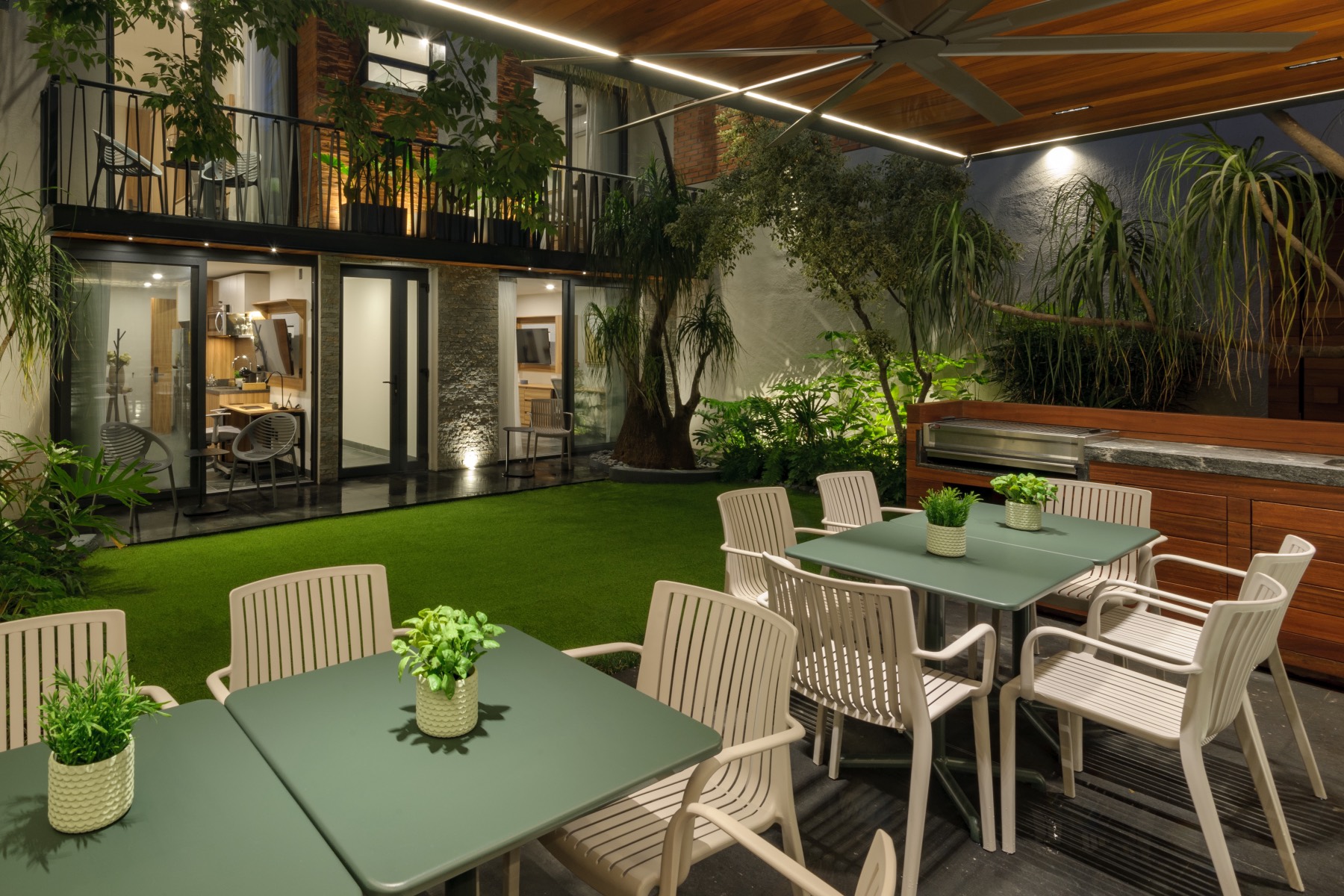 Terraza social con jardín y comedor exterior al atardecer